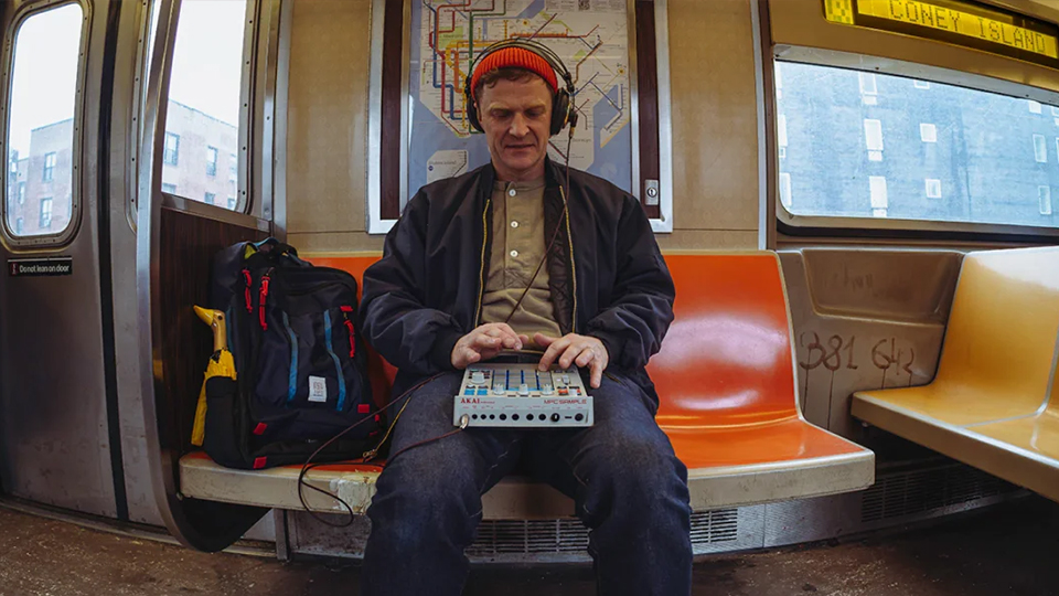 Man with Akai Professional MPC Sample Sequencer on train