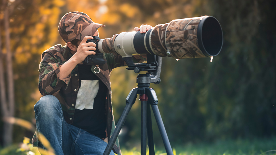 Man with tripod taking a photo with a large lens